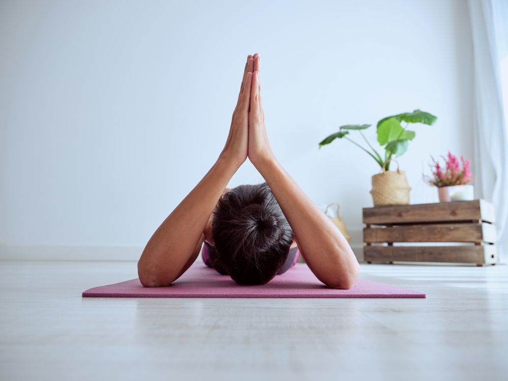 Unrecognizable woman practicing yoga at home