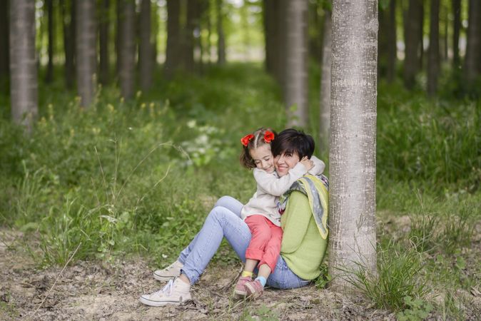 Daughter sitting on mother in forest