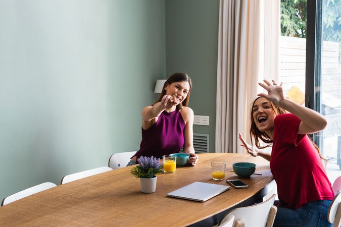 Joyful women having lunch and outstretching arms towards camera