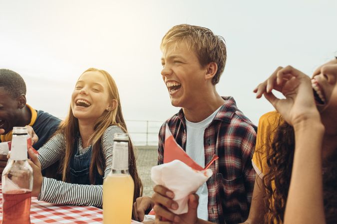 Close up of teenage friends laughing and having fun sitting in a restaurant outside