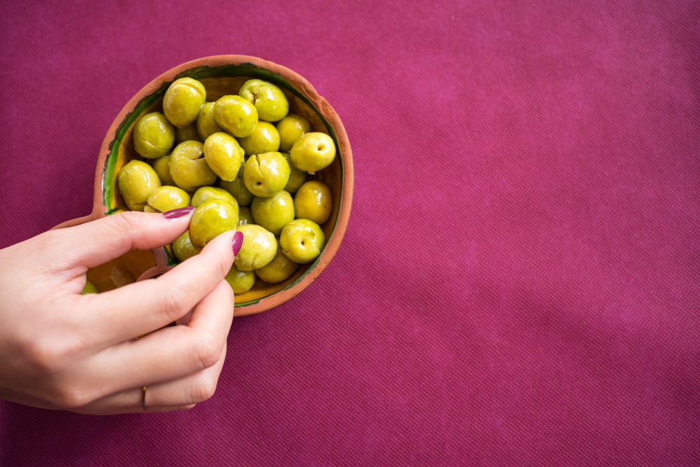 Asian woman eating olives in restaurant