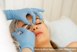 Cosmetologist at med spa injecting botox between eyes in female client 5o8p94