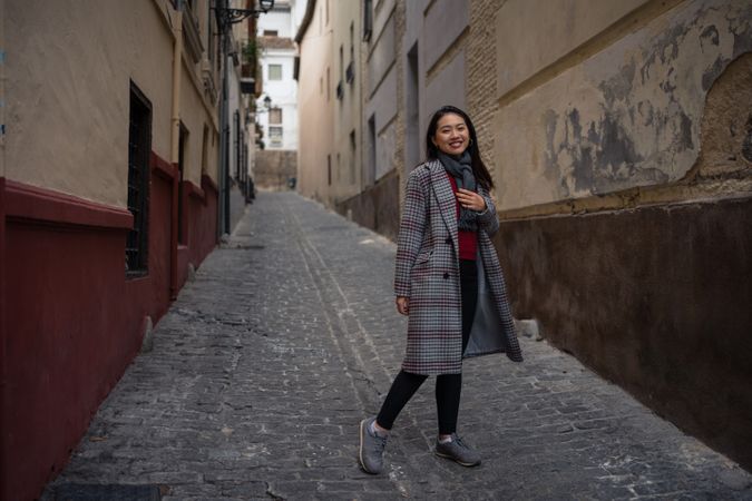 Joyful Asian resting female hiking on old rocked narrow street