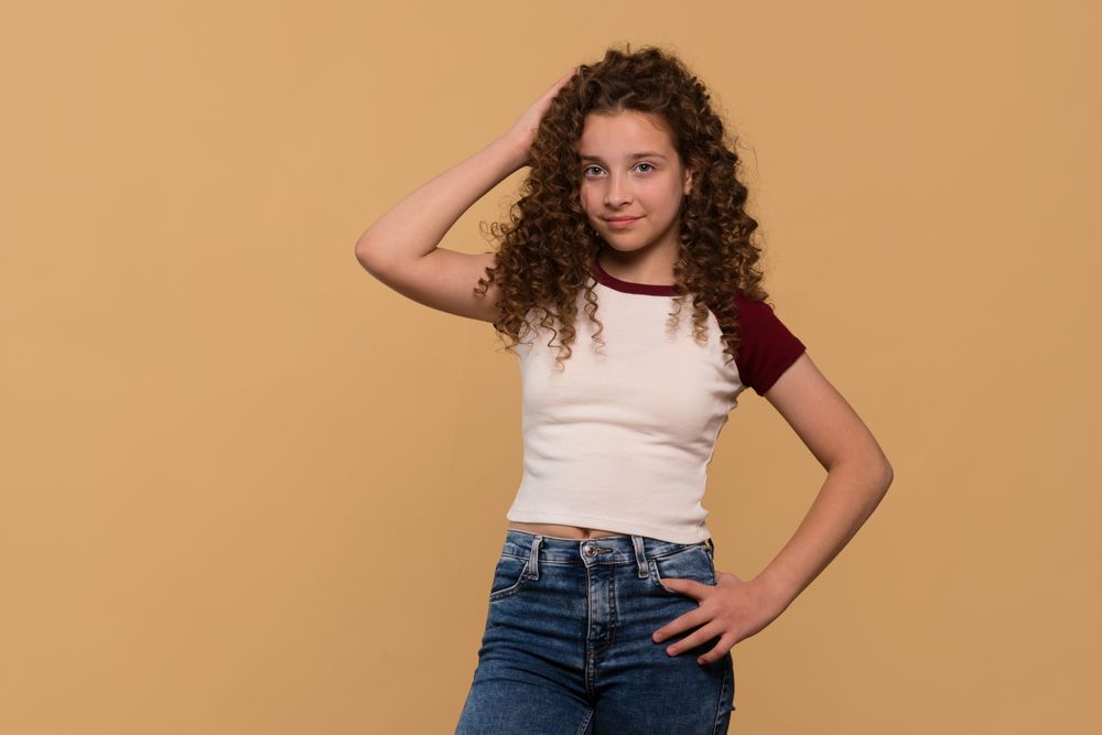 Young girl posing with hand on head, smiling confidently
