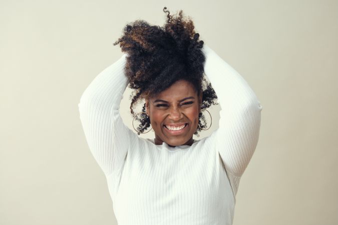 Portrait of joyful Black woman running her hands through her afro hair