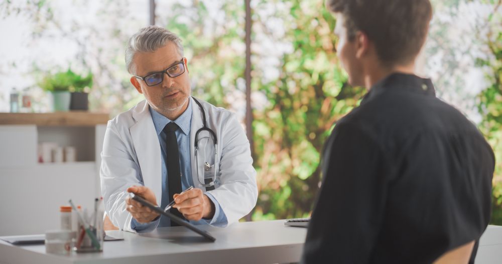 Family Doctor Working Behind a Desk in Hospital Office