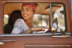 Smiling woman sitting in vintage car looking out of the window 5lneeb