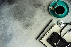 Top view of coffee cup with stethoscope, phone and notepad with copy space