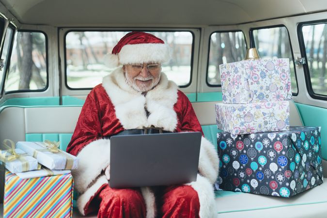 Santa Claus working at laptop in van