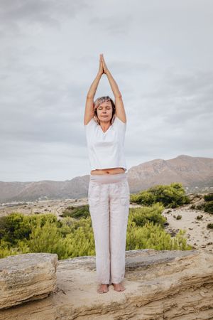 Barefoot woman meditating on stone