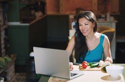 Woman at the table with vegetables working via laptop