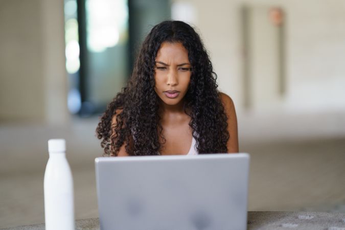 A focused woman diligently working on her laptop in a modern and stylish workspace environment