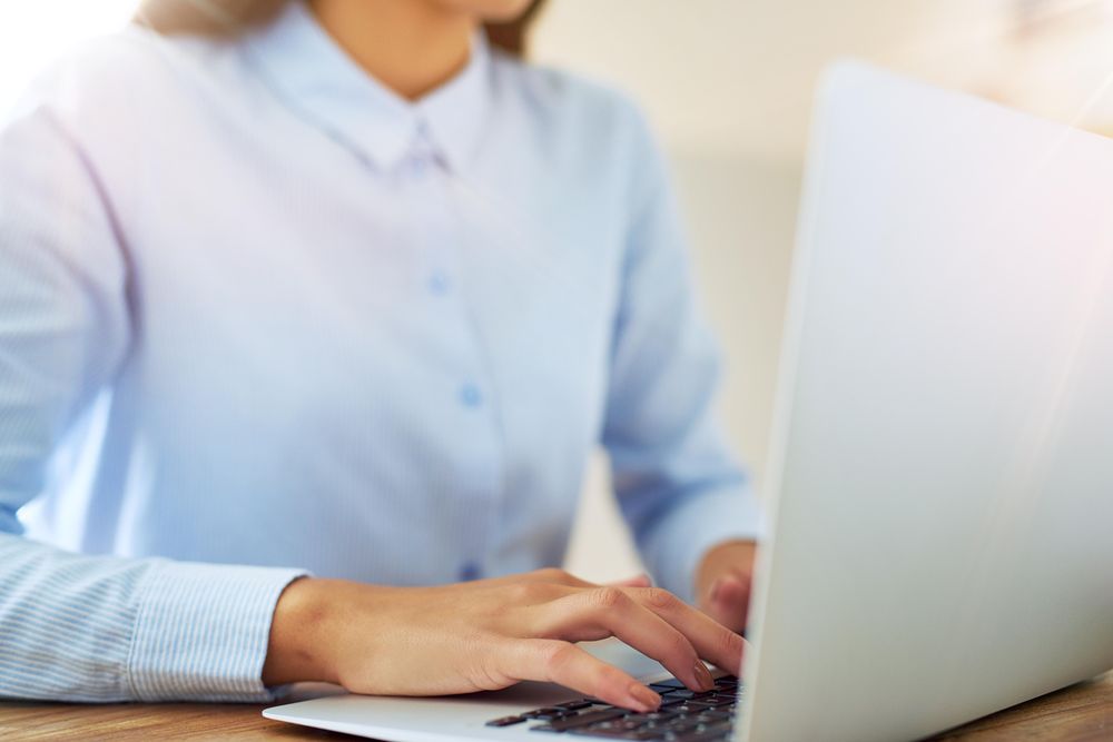 Close up of woman using laptop on wooden desk