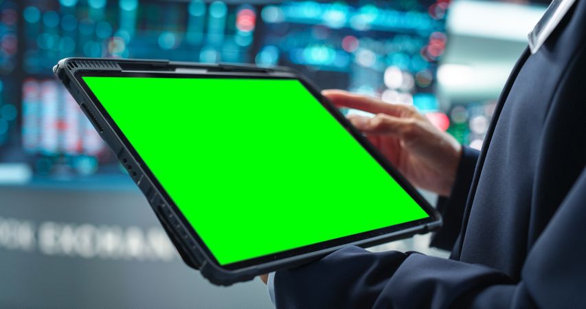 Person Holding a Tablet Computer with Green Screen Mock Up Display. Stock Exchange Application Template.