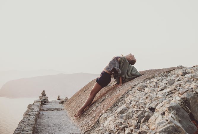 Woman leaning back on castle wall overlooking sea