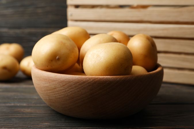 Bowl full of potatoes next to wooden box