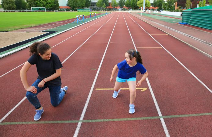 Two sisters stretching on running track