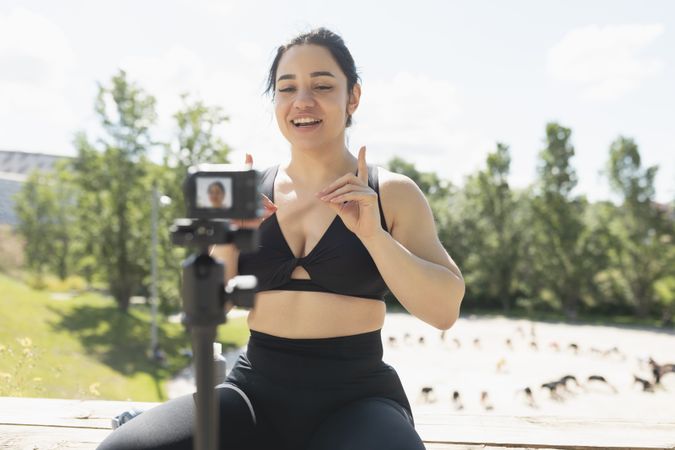 A young woman records herself on video, to explain to her followers, how to perform an exercise and sport workout