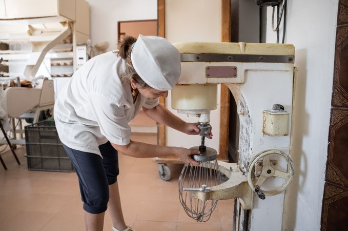Unrecognizable baker woman setting an industrial beater to prepare cupcakes