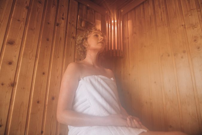 Woman sitting in a wooden sauna spa taking steam bath