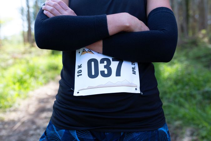 Unrecognizable female trail athlete posing with race number