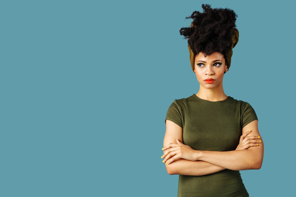 Studio shoot of contemplative Black woman with arms crossed