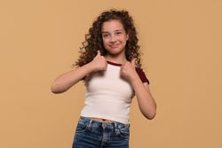 Young girl giving double thumbs-up, smiling confidently