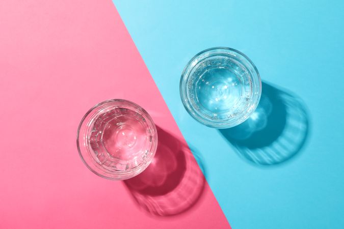 Two glasses of water on duo tone pink and blue background