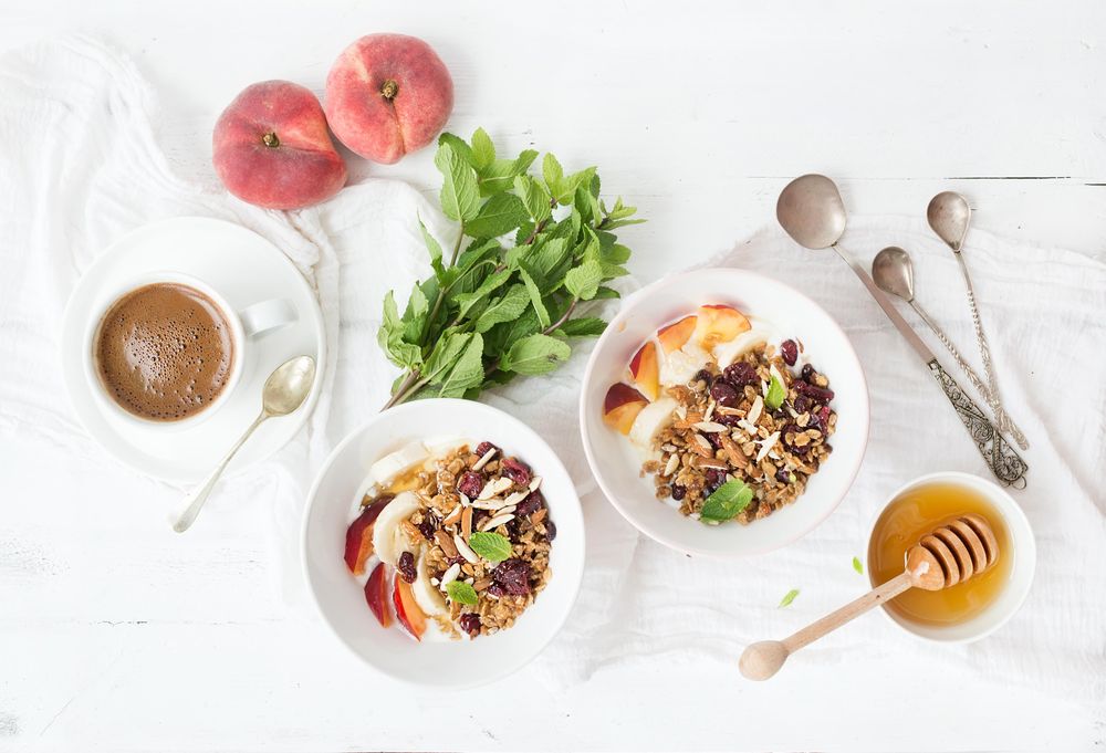 Breakfast of yogurt bowls, coffee, and peaches