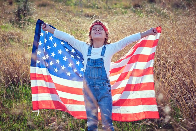 Happy kid with USA flag in yellow grass