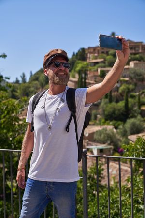 Middle aged man taking selfie on smartphone in old city