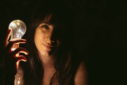 Thoughtful woman with burning lightbulb in darkness