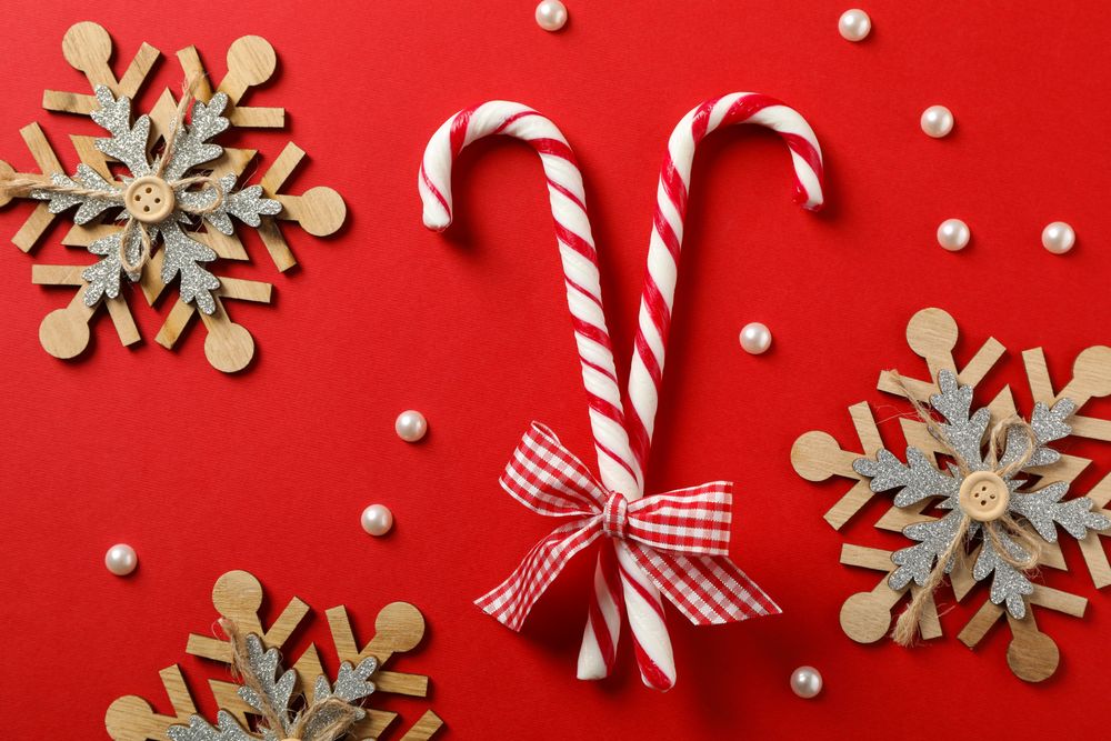 Candy canes and decorative snowflakes on red background, top view