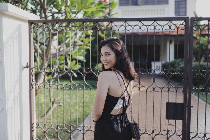 Woman in dark dress standing near dark dark metal gate
