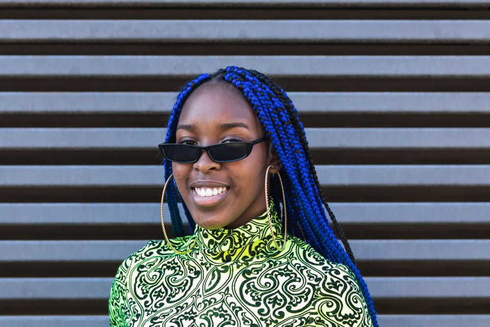 Smiling Black woman in trendy clothes in city