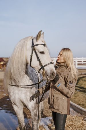 Warm dressed woman with gray horse outside