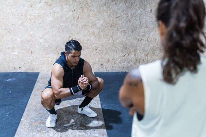 Hispanic sportsman near faceless woman in gym