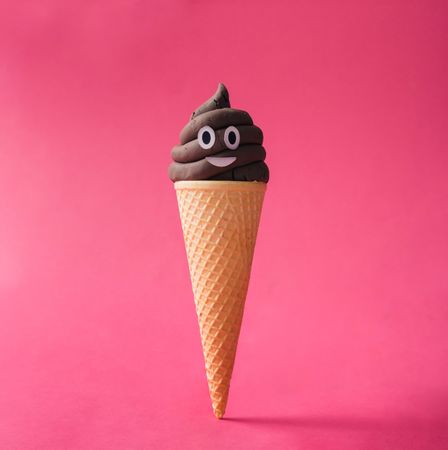 Poop emoticon in ice cream cone on pink background