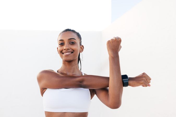 Smiling woman stretching arms before exercises