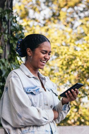 Black Latina woman using a smartphone in the park on a summer day.n