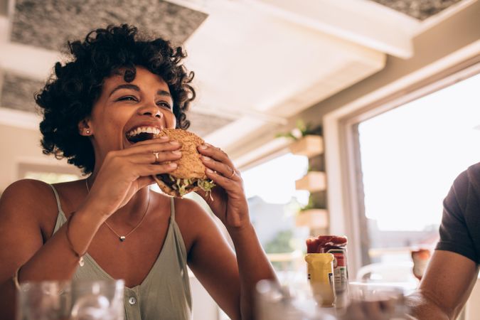 Black woman about to bite into a burger at a restaurant