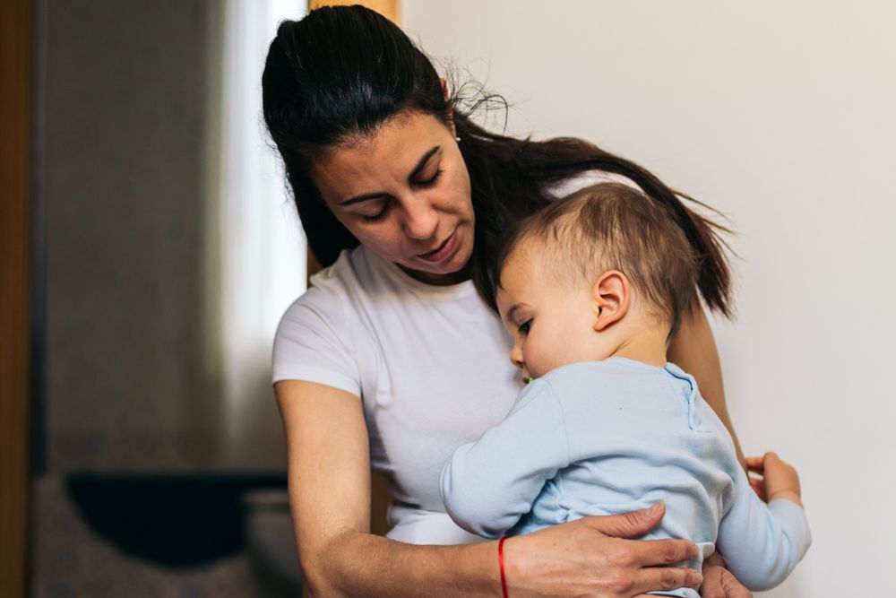 mother hugging her baby sitting at home