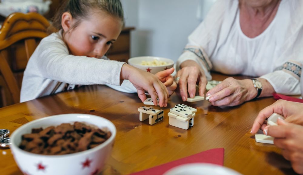 Little girl playing dominoes with mother and grandmother