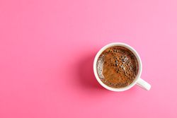 Cup of coffee on color background, space for text
