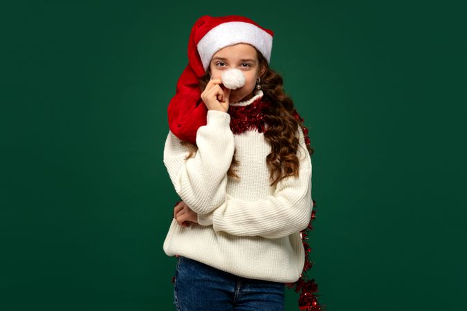 Girl in Santa hat holding pompom to nose