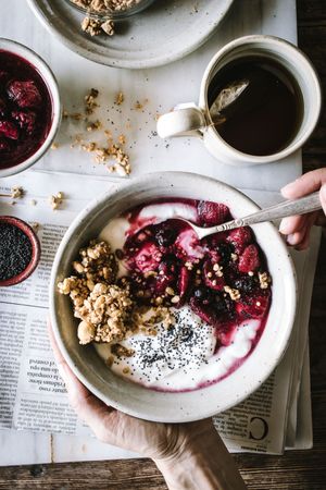 Delicious breakfast bowl with quinoa, rice and groats near tea cup and newspaper