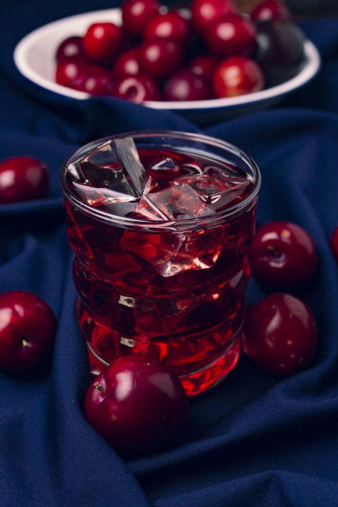 Red beverage near fresh fruits on cloth