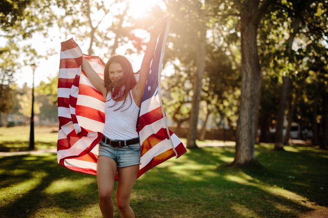Smiling young woman with USA flag at park
