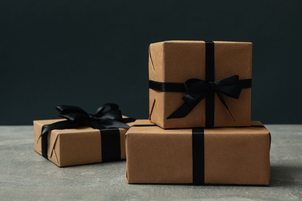 Craft gift boxes with bow on gray table against dark background