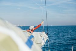 Man on sailboat arranging ropes